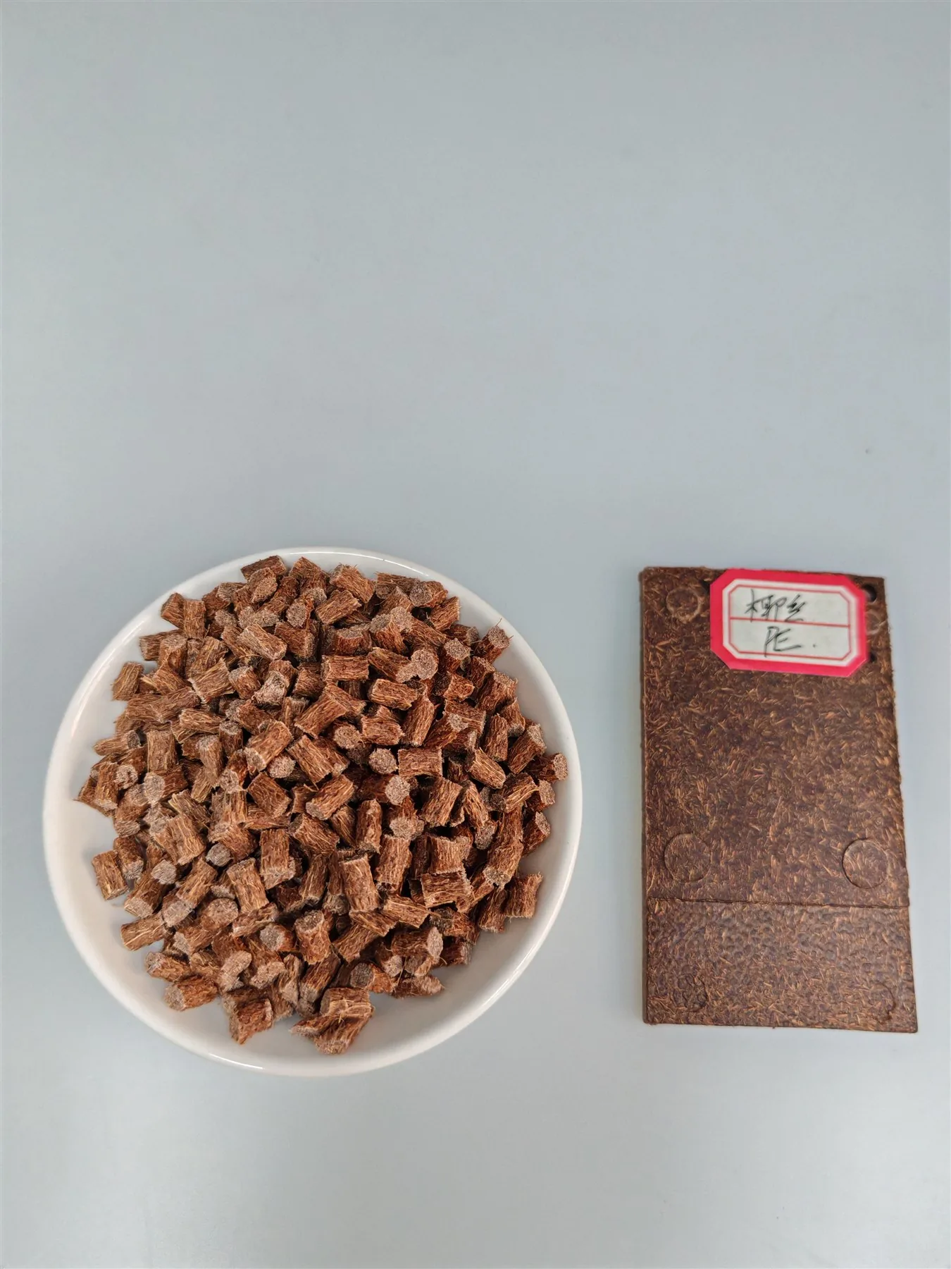 样品皿中的椰丝纤维PE母粒颗粒与旁边的注塑样板